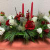 Red and white flowers with two tapered candles, pine boughs and pine