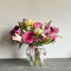 A darling arrangement of roses and lily alongside a floral mix. 