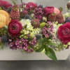 Ranunculus, wax flower, scabiosa, thistle, hydrangea, and hellebores in a low long