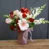 A beautiful arrangement in a decorative keepsake container. With soft pops of