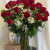 These two dozens of red roses in a clear vase are accented
