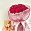 A round bouquet of roses wrapped in pink paper, accented with pearl-decorated