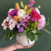 An arrangement in a ceramic pot, with lilies, stalk, anemones , roses