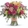 Bright pink roses, peach lilies, and assorted summer flowers over flowing in