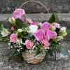 This arrangement is in a cute basket filled with pink roses, alstroemeria