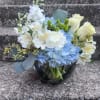This arrangement has blue hydrangea, white carnations, white alstroemeria, green Hypericum, white