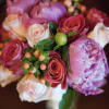 A compact arrangement of roses, berries and other seasonal blooms in feminine