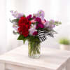 A striking mix of rich red roses, soft blush spray roses, vibrant