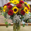 Combination of sunflowers and red roses with filler and greenery.