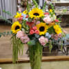Large glass vase with sunflowers, spray roses, snapdragons, calla lilies, stock, carnations