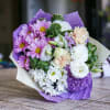 Purple Rain Wrapped Bouquet features purples, whites and peach colors.

Our loose bunches