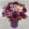 A playful array of bold purple and pink flowers including roses, daisies