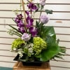 A very modern floral arrangement, with purple orchids, mini bamboo and a
