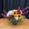 A radiant mix of cheerful sunflowers, soft blush roses, and vibrant seasonal