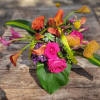 Festive and colorful mixture of seasonal blossoms. Executed in clear glass container