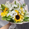 This cheerful mix of sunflowers, elegant lilies, and classic daisies brings the