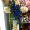 A beautiful cross-shaped spray with white carnations and blue roses.