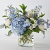 A lavish bouquet of light blue, white flowers, and lush greenery in