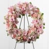 Round floral wreath on a easel, pastel tones of pink and white.