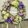 Round wreath with Green, purple and lavender flowers on an easel.