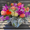 This arrangement is a new design using peaches, oranges and purples. The