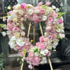 The stand includes the wood easel.
Pink roses, white hydrangeas, spray roses, orchids
