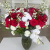 Red roses and white orchids arranged in a clear glass vase