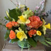 A bright display of yellow daffodils, iris, and orange roses in a