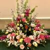 This urn arrangement has Stargazer lilies, pink roses, hot pink garden roses