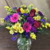 This vase includes hot pink gerberas, red roses, purple carnations, yellow alstroemeria