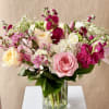 Romantic variety of fresh flowers arranged in a clear glass vase. 
