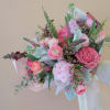 An assortment of pink hued flowers wrapped in premium paper.  (Bouquet