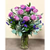 Dozen purple roses vased with greenery and filler flower.