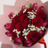 A premium handcrafted bouquet featuring deep red roses, tulips, and soft baby&rsquo;s