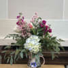 A silver vase filled with fresh pink flowers with pops of other