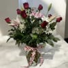 Roses and pink lilies arranged in a vase, accented with lush greens
