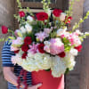 Large red hatbox arrangement with roses, hydrangeas, and lilies