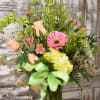 A beautiful spring arrangement with soft pastels of pinks, oranges, peach, and