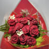 Twelve premium red roses arranged in elegant cellophane wrapping with lush green