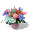 Coral roses and a coral opaque vase paired with blue agapanthus and