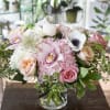 Monochromatic light pink flowers along with designer roses, arranged in a clear