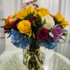 Colorful bouquet of roses, sunflowers, and hydrangeas in a glass vase