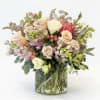 This arrangement is in a cylinder and has protea, stock, roses and