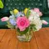 A petit arrangement in a low cylinder vase featuring hydrangea, roses and