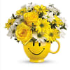 An adorable smiley mug filled with white and yellow seasonal flowers. Will
