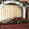 This vivid presentation features a lush red rose casket spray flanked by