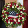 This patriotic wreath pays tribute with a bold ring of red roses