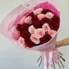 Red and pink roses, accompanied by greenery and decorative wrapping paper. All