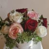Pave arrangement of a dozen mixed roses. Leaf-wrapped glass vase may be