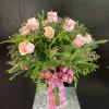 A dozen light pink roses beautifully arranged in a cylinder glass vase.